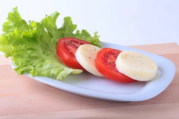 Порция моцареллы с помидорами, листом салата и бальзамическим соусом на белой тарелке. селективный фокус крупным планом . — стоковое фото
