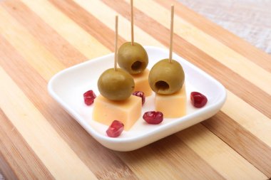 Peynirli kanepeler zeytin ve ahşap tepsi nar taneleri ile yakın çekim.