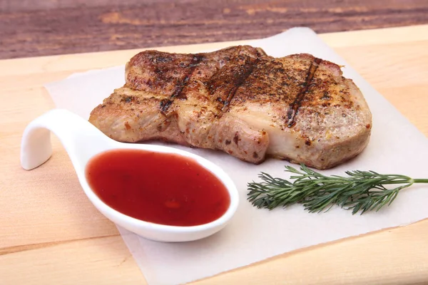 Chuleta de cerdo a la parrilla con salsa de arándano en plato sobre tabla de madera — Foto de Stock