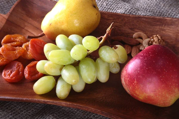 Frutos orgânicos frescos na bandeja de serviço de madeira. Maçã, pêra, uvas, frutos secos e nozes variados . — Fotografia de Stock