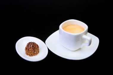 Klasik espresso kahve ve pralin siyah arka plan üzerine beyaz fincan.