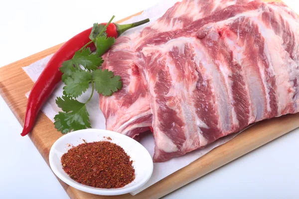 Raw pork ribs with herbs and spices on wooden board. Ready for cooking. — Stock Photo, Image