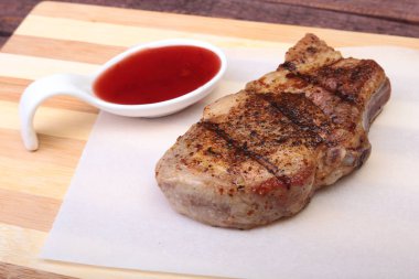 ızgara domuz eti ile kızılcık sosu ahşap tahta üzerinde plaka üzerinde