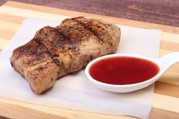 ızgara domuz eti ile kızılcık sosu ahşap tahta üzerinde plaka üzerinde