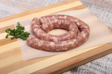 Ahşap arka plan üzerinde baharatlar ile ev yapımı çiğ sosis.