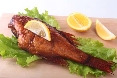 Füme balık ve beyaz arka plan üzerinde izole tahta kesme tahta üzerinde yeşil marul yaprakları limon.