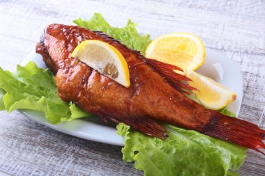 Füme balık ve beyaz arka plan üzerinde izole tahta kesme tahta üzerinde yeşil marul yaprakları limon.