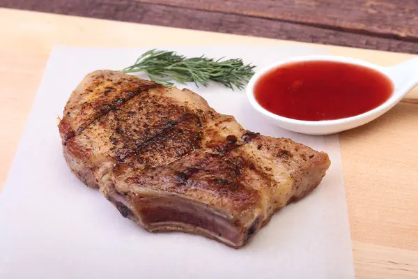 Chuleta de cerdo a la parrilla con salsa de arándano en plato sobre tabla de madera — Foto de Stock