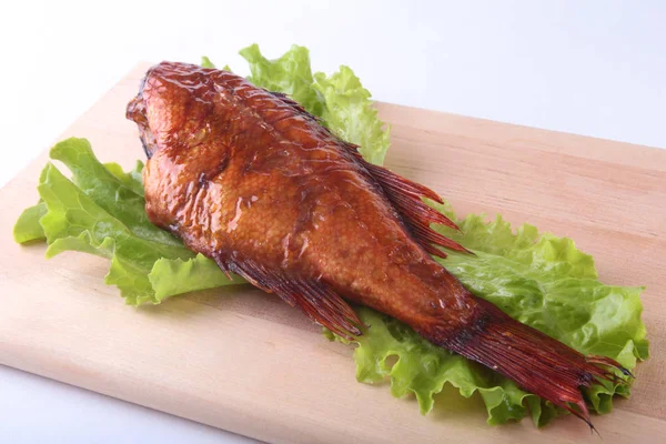 Füme balık ve beyaz arka plan üzerinde izole tahta kesme tahta üzerinde yeşil marul yaprakları limon.