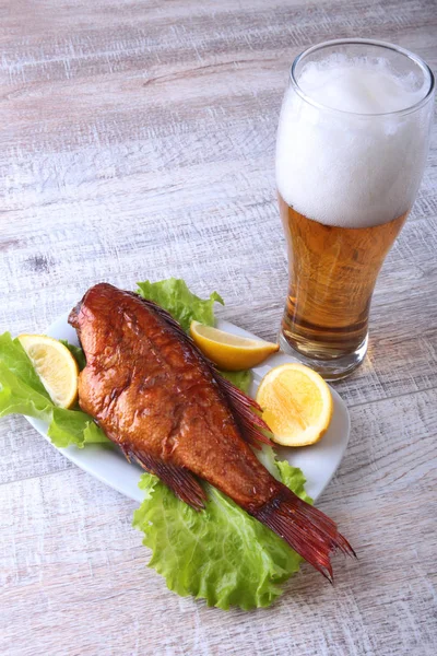 Füstölt hal, citromos, zöld saláta levelek, a fa vágódeszka és üveg sör elszigetelt fehér background. — Stock Fotó