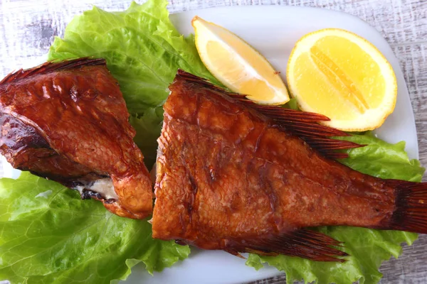 Pescado ahumado y limón sobre hojas de lechuga verde sobre tabla de cortar de madera aislada sobre fondo blanco . — Foto de Stock