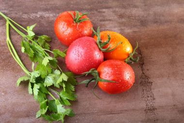 ahşap arka plan üzerinde izole yeşil yaprakları ile çeşitli taze domates