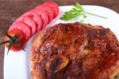ızgara domuz pirzolası dilimlenmiş domates ve ahşap masa sosu ile.