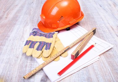 Turuncu kask, koruyucu gözlük, eldiven ve ahşap arka plan üzerinde ölçüm bandı.