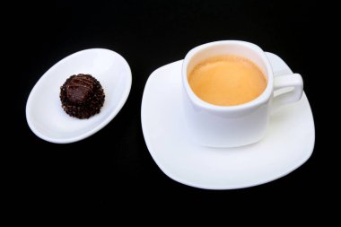 Klasik espresso kahve ve pralin siyah arka plan üzerine beyaz fincan.