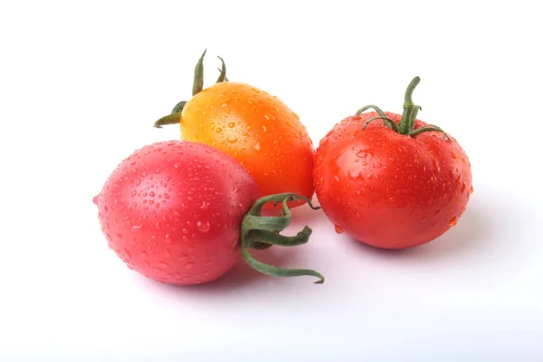 Сортированные свежие помидоры с зелеными листьями на белом фоне — стоковое фото