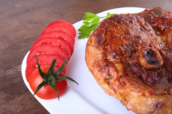 Chuleta de cerdo a la parrilla con tomate en rodajas y salsa sobre mesa de madera . — Foto de Stock