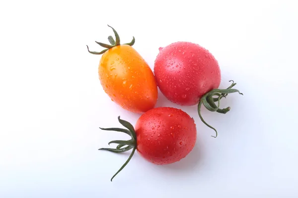 Сортированные свежие помидоры с зелеными листьями на белом фоне — стоковое фото