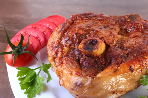 Жареная свиная отбивная с нарезанным помидором и соусом на деревянном столе . — стоковое фото