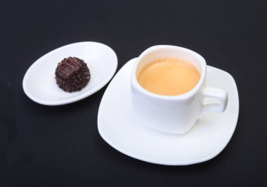 Klasik espresso kahve ve pralin siyah arka plan üzerine beyaz fincan.