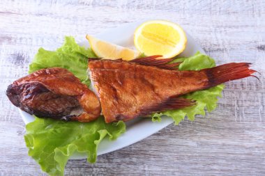 Füme balık ve beyaz arka plan üzerinde izole tahta kesme tahta üzerinde yeşil marul yaprakları limon.