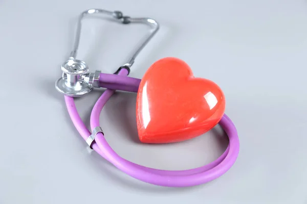 Estetoscopio, corazón rojo, gafas y medidor de presión arterial sobre fondo blanco. Enfoque selectivo . — Foto de Stock