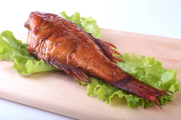 Füme balık ve beyaz arka plan üzerinde izole tahta kesme tahta üzerinde yeşil marul yaprakları limon.