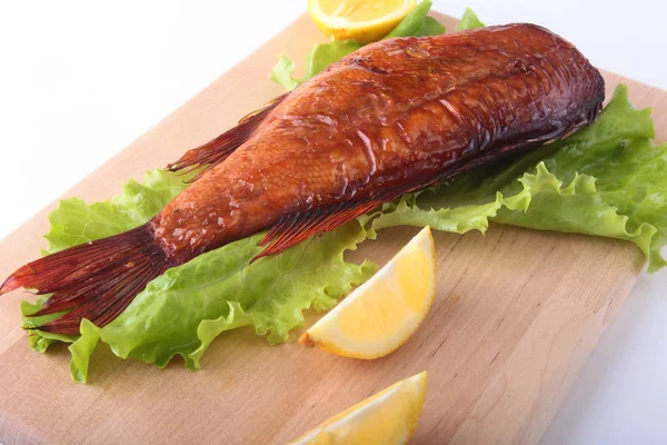 Füme balık ve beyaz arka plan üzerinde izole tahta kesme tahta üzerinde yeşil marul yaprakları limon.
