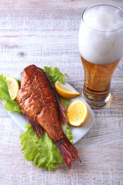 Füstölt hal, citromos, zöld saláta levelek, a fa vágódeszka és üveg sör elszigetelt fehér background. — Stock Fotó