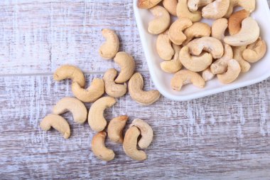 ahşap arka plan üzerinde beyaz kase fındık kaju fıstığı. Seçici odak.