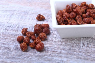 Ahşap arka plan üzerinde beyaz bir kapta şekerli fındık. Fındık şeker sır içinde. Seçici odak.