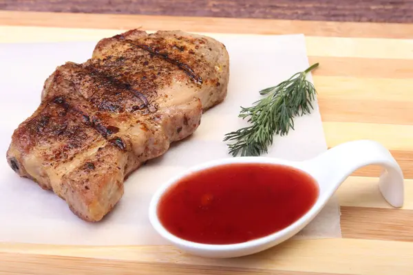 ızgara domuz eti ile kızılcık sosu ahşap tahta üzerinde plaka üzerinde