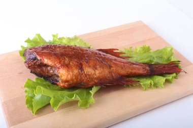 Füme balık ve beyaz arka plan üzerinde izole tahta kesme tahta üzerinde yeşil marul yaprakları limon.