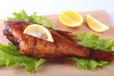 Füme balık ve beyaz arka plan üzerinde izole tahta kesme tahta üzerinde yeşil marul yaprakları limon.