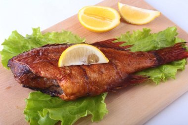 Füme balık ve beyaz arka plan üzerinde izole tahta kesme tahta üzerinde yeşil marul yaprakları limon.