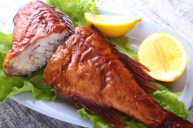 Füme balık ve beyaz arka plan üzerinde izole tahta kesme tahta üzerinde yeşil marul yaprakları limon.