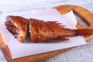 Füme balık ve beyaz arka plan üzerinde izole tahta kesme tahta üzerinde yeşil marul yaprakları limon.