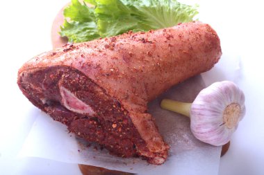 Çiğ domuz knuckle, sarımsak, baharat ve marul yaprakları bir kesme tahtası üzerinde. Seçici odak. Hazır yemek pişirmek için.