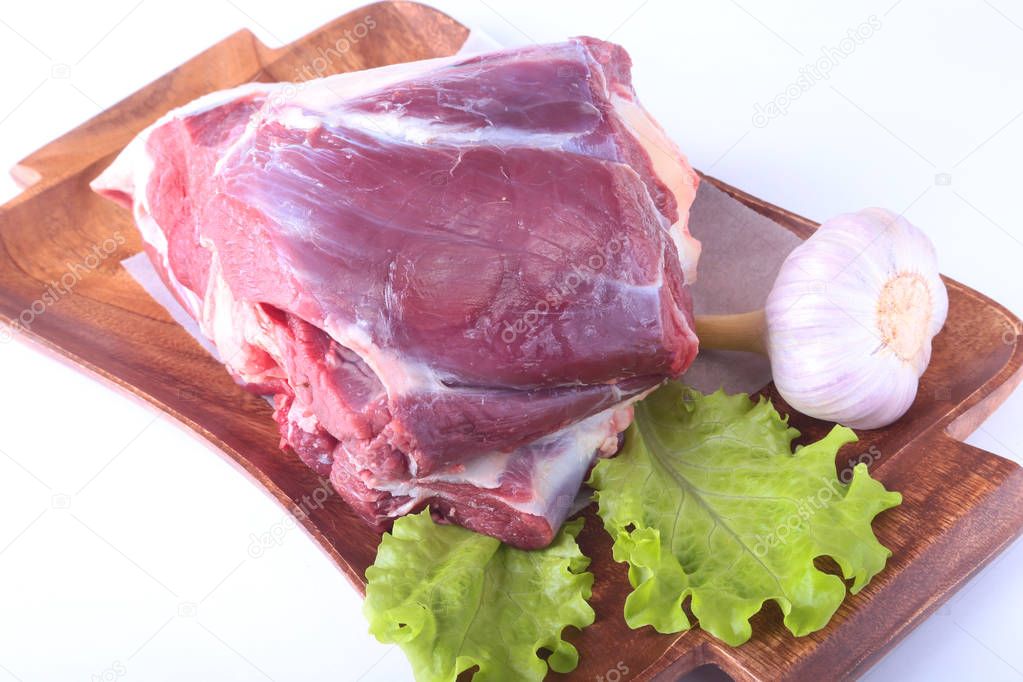 Raw beef shanks, garlic and lettuce leaf on wooden desk isolated on white background from above and copy space. ready for cooking.