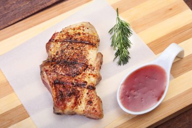 ızgara domuz eti ile kızılcık sosu ahşap tahta üzerinde plaka üzerinde