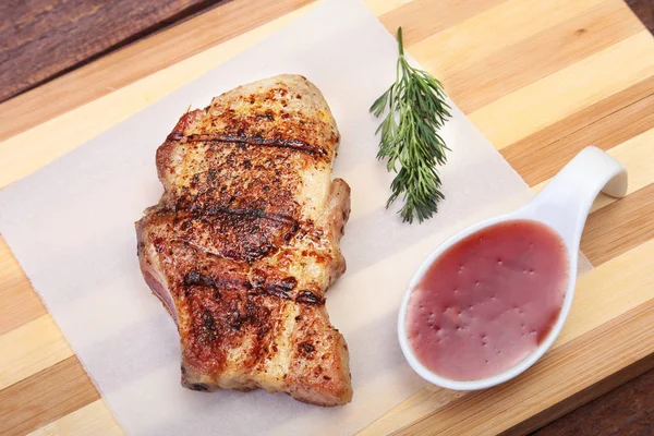 ızgara domuz eti ile kızılcık sosu ahşap tahta üzerinde plaka üzerinde