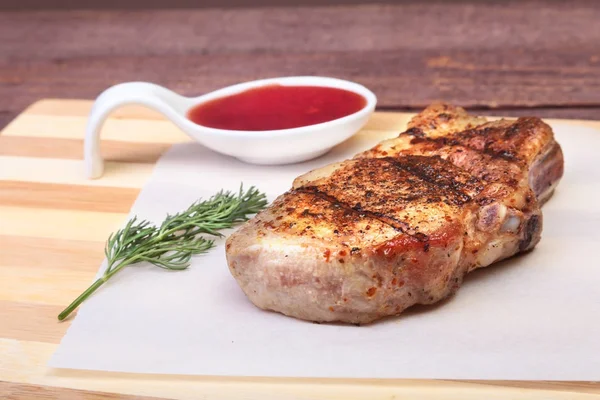 ızgara domuz eti ile kızılcık sosu ahşap tahta üzerinde plaka üzerinde