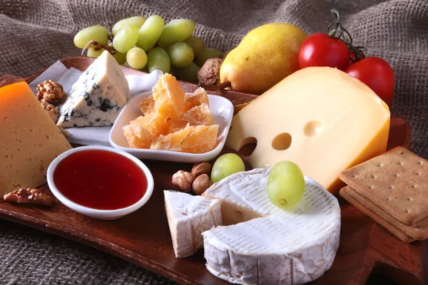 Assortiment van kaas met fruit, druiven en noten op een houten dienblad. — Stockfoto