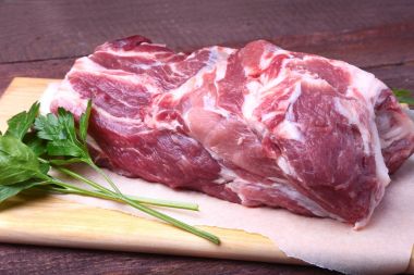 Çiğ domuz eti boyun pirzola et maydanoz ot ile taş bir arka plan üzerinde bırakır. Hazır yemek pişirmek için.