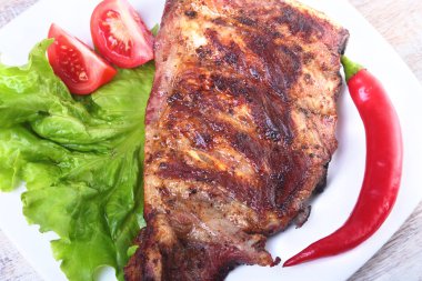 Domuz kaburga ızgara ve biber domates ile beyaz tabağına marul yaprakları