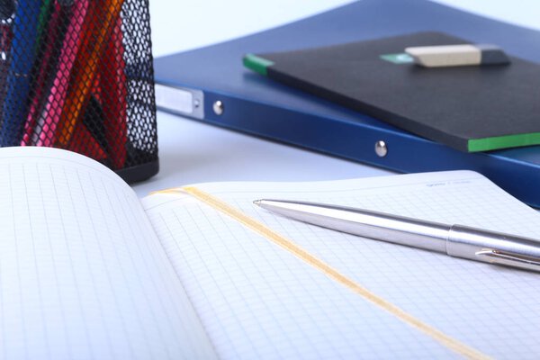 Colorful notebooks and office supplies on white table.