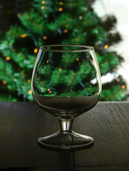 Glas für Cognac, Brandy oder Whiskey auf dem Hintergrund eines Weihnachtsbaums. — Stockfoto