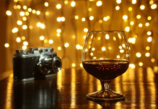 Kieliszek brandy lub koniaku i retro camera na drewnianym stole — Zdjęcie stockowe