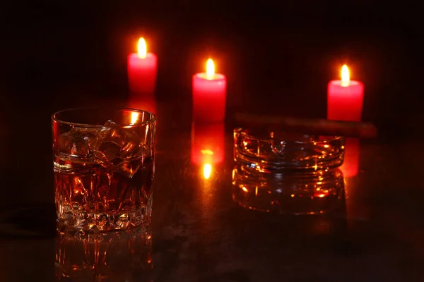 Glass of cognac or whiskey, cigar and red candles on a wooden background. christmas decoration. — Stock Photo, Image