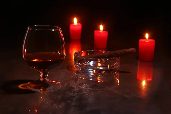 Bicchiere di cognac o whisky, sigari e candele rosse su fondo di legno. decorazione natalizia . — Foto Stock